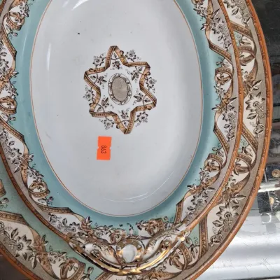 Antique porcelain serving platters featuring light blue borders, floral ribbon transferware designs, and gilded rim details.