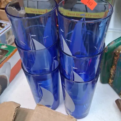 Set of six cobalt blue glass tumblers etched with white sailboat motifs, stacked in two columns of three.