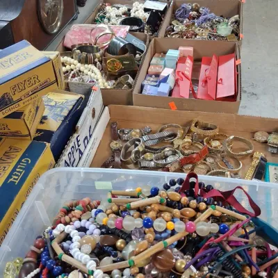 Large assortment of vintage costume jewelry, wristwatches, mantle clocks, and boxed American Flyer model train accessories spread across...