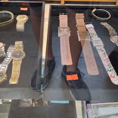 Collection of men's and women's wristwatches, featuring metal link and leather-strapped styles including Coach and Chanel...