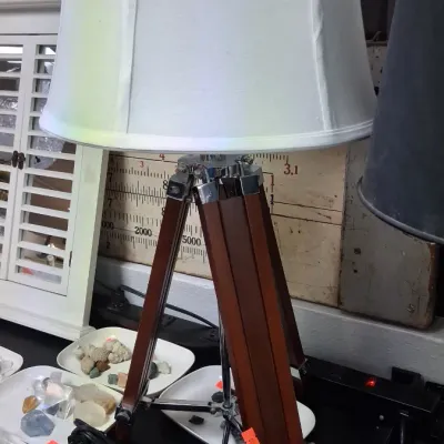 Nautical-style tripod table lamp featuring a dark wood and chrome surveyor's tripod base topped with a large white fabric drum shade.
