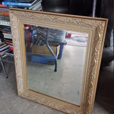 Large rectangular wall mirror featuring an ornate, gold-finished composite frame with embossed baroque-style scrollwork.
