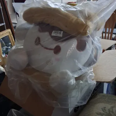 Large Sanrio Pompompurin plush character toy wrapped in protective plastic, stored inside a cardboard box.