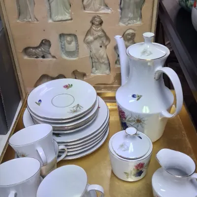 Vintage white porcelain coffee and tea service with alpine floral motifs, silver rim detailing, and matching tray, displayed alongside a...