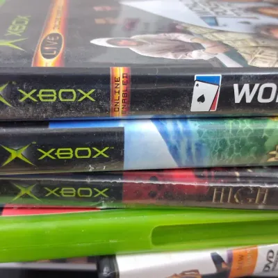 Stack of original Xbox video games including World Poker Tour and Harry Potter Quidditch World Cup in their original plastic cases.