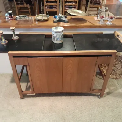 Sale Photo Thumbnail #6: Mid-century modern rolling teak bar cart with black laminate flip-top surfaces, wooden handles, and a cabinet base.