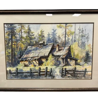 Sale Photo Thumbnail #48: Framed watercolor painting depicting a rustic log cabin in a pine forest, signed by the artist in the lower left corner and set in a dark wooden frame with a light mat.