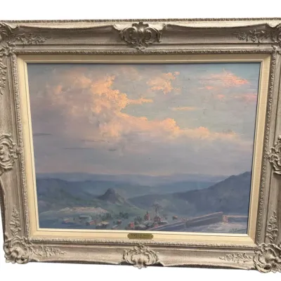 Sale Photo Thumbnail #49: Framed oil painting depicting a valley landscape with clouds and distant mountains, set in an ornate painted cream and gold wood frame.