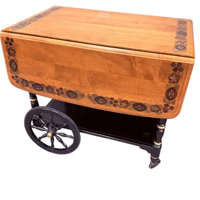 Sale Photo Thumbnail #33: Vintage wooden drop-leaf tea cart featuring floral marquetry inlay, spoke wheels, and a black-painted lower shelf.