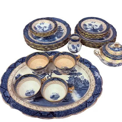 Sale Photo Thumbnail #37: Vintage blue and white Willow pattern porcelain tea service with gilded trim, including cups, saucers, plates, creamer, covered sugar bowl, and serving tray.