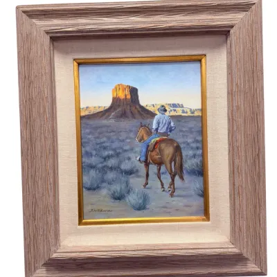 Sale Photo Thumbnail #64: Framed Western oil painting on board signed by Bill Edwards, depicting a cowboy on horseback facing a desert mesa. Presented in a rustic textured wooden frame with a fabric liner.
