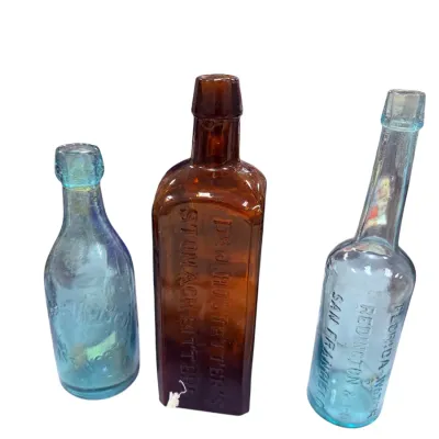Sale Photo Thumbnail #20: Trio of antique embossed glass bottles including an amber Dr. J. Hostetter's Stomach Bitters bottle and two light aqua medicine bottles.