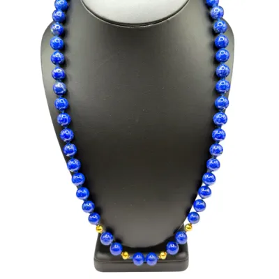 Sale Photo Thumbnail #76: Single strand lapis lazuli beaded necklace featuring polished cobalt blue spherical beads accented with small gold spacer beads, displayed on a black bust.