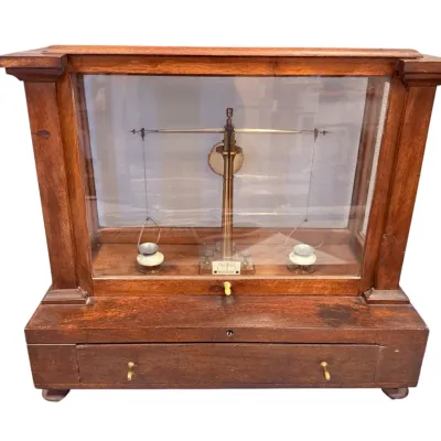 Sale Photo Thumbnail #63: Vintage brass analytical scale housed in a glass-paneled wooden display case featuring a single bottom drawer.