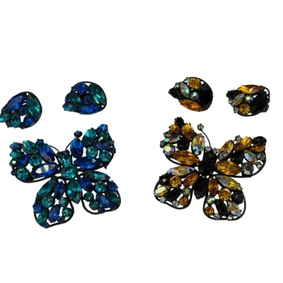 Sale Photo Thumbnail #70: Two sets of vintage rhinestone butterfly brooches with matching clip-on earrings, featuring dark metal settings with blue-teal and yellow-amber aurora borealis stones.