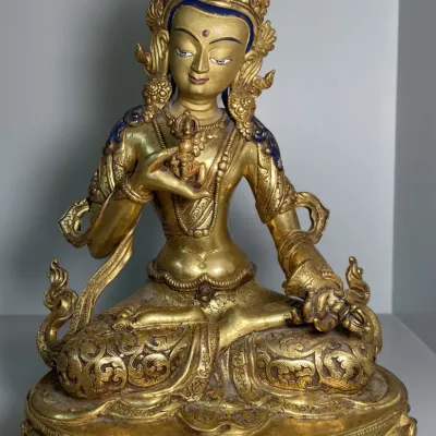 Sale Photo Thumbnail #58: Gilt bronze Sino-Tibetan statue of Vajrasattva seated in dhyanasana on a lotus base, featuring intricate scrollwork and painted facial details.