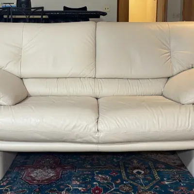 Sale Photo Thumbnail #83: Off-white leather two-cushion loveseat featuring padded pillow-top armrests and a modern low-profile silhouette.