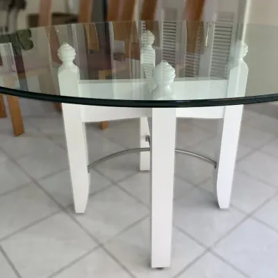Sale Photo Thumbnail #19: Round dining table featuring a thick glass top set on a white painted wooden base with turned finials and metal stretchers.