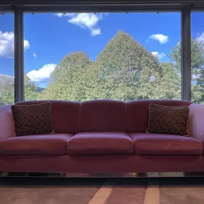 Sale Photo Thumbnail #76: Hollywood Regency style dusty rose upholstered sofa featuring polished brass trim and two accent pillows.
