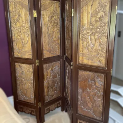 Sale Photo Thumbnail #82: Four-panel vintage Asian-style room divider with intricately hand-carved relief panels depicting traditional figures and architectural scenes in a rich dark wood frame.