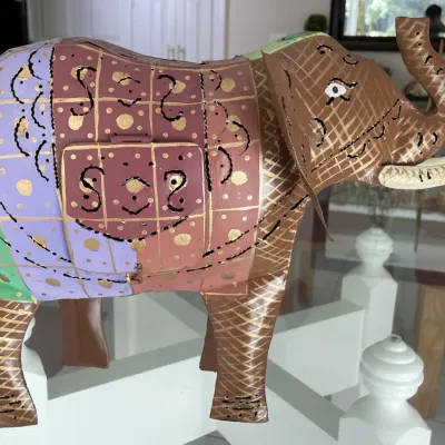 Sale Photo Thumbnail #62: Decorative hand-painted metal elephant sculpture with a small side hatch door, featuring colorful geometric and gold accent details.