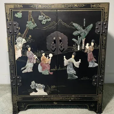 Sale Photo Thumbnail #5: Vintage Asian black lacquer cabinet featuring carved jade and soapstone relief figures of court ladies against a painted landscape with brass hardware.