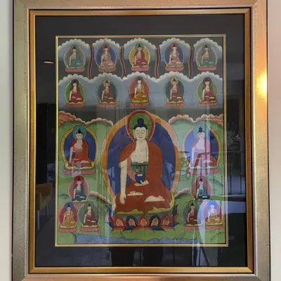 Sale Photo Thumbnail #49: Framed Tibetan thangka painting depicting Buddha surrounded by smaller deities, set in a metallic gold double frame with dark matting.
