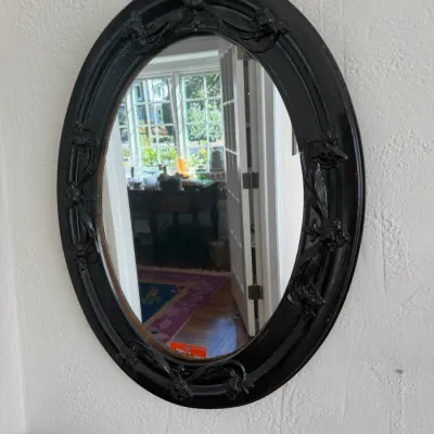 Sale Photo Thumbnail #115: Vintage oval wall mirror with a black-painted ornate floral molded frame.