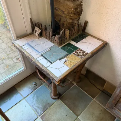 Sale Photo Thumbnail #75: Rustic handcrafted corner table with a tiled mosaic top, natural wood branch legs, and a driftwood-style back border.