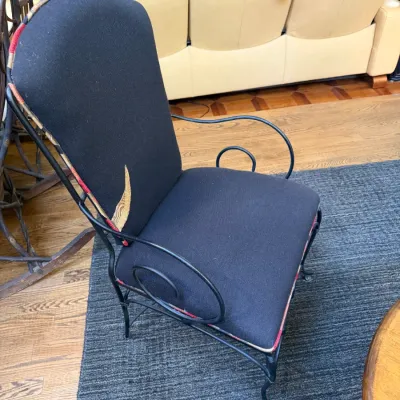 Sale Photo Thumbnail #129: High-back wrought iron armchair featuring scrolling armrests and black fabric upholstery with patterned trim accents.