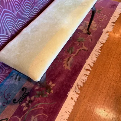 Sale Photo Thumbnail #100: Long traditional upholstered bench featuring pale yellow velvet fabric and carved cabriole dark wood legs, shown resting on a floral runner rug.