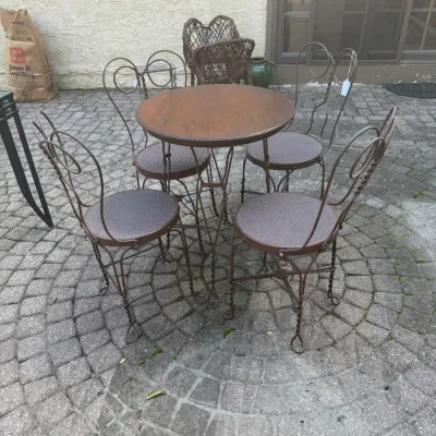 Sale Photo Thumbnail #194: Vintage iron ice cream parlor bistro set featuring a round wooden-top table paired with four twisted wire loop-back chairs.