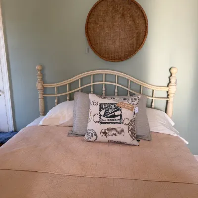 Sale Photo Thumbnail #170: Off-white wooden spindle queen bed frame paired with a large round woven wall hanging mounted above the headboard.