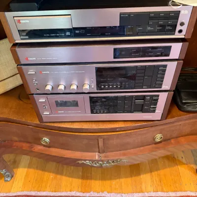 Sale Photo Thumbnail #165: Vintage Kyocera stereo component system stack, featuring a compact disc player, remote control center, stereo tuner amplifier, and cassette deck, circa 1980s.