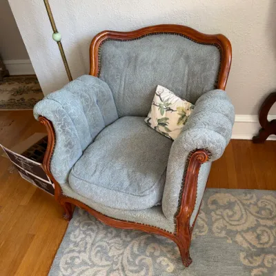 Sale Photo Thumbnail #135: French Provincial style armchair upholstered in light blue jacquard fabric, featuring a carved wood frame with nailhead trim.