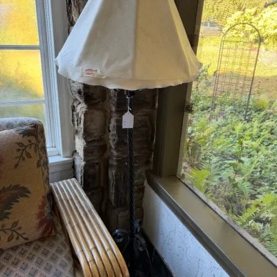 Sale Photo Thumbnail #86: Black wrought iron floor lamp with twisted stem and white fabric shade, positioned next to a bamboo armchair in a sunroom.