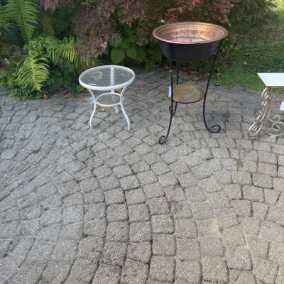 Sale Photo Thumbnail #193: Collection of outdoor patio furniture including a black wrought iron stand with a copper basin, a white metal side table with a glass top, and a scrolled metal plant stand.