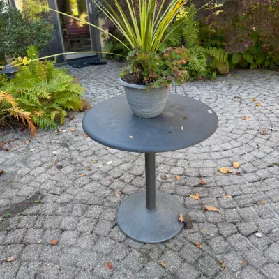 Sale Photo Thumbnail #122: Round dark gray metal patio bistro table featuring a weighted pedestal base, displayed outdoors with a potted planter on top.