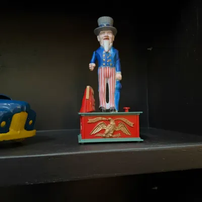 Sale Photo Thumbnail #144: Vintage cast iron Uncle Sam mechanical bank featuring painted details and an embossed eagle emblem.