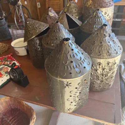 Sale Photo Thumbnail #211: Collection of rustic punched tin candle lanterns in various sizes with conical tops, displayed on a wooden table.