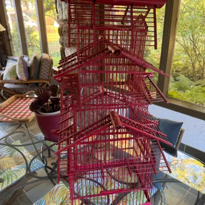 Sale Photo Thumbnail #77: Vintage red wooden pagoda-style birdcage featuring intricate tiered roofs and a hanging ring at the top.