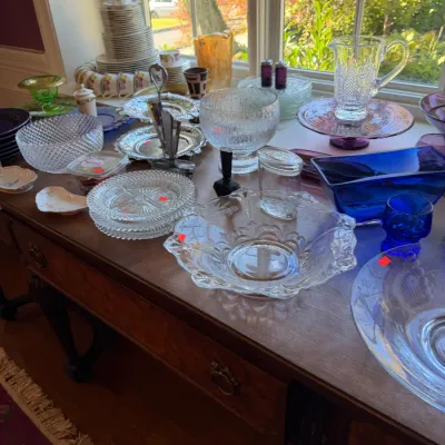 Sale Photo Thumbnail #104: Collection of vintage glassware, including cobalt blue, cut glass, pressed glass bowls, and silver-plate serving pieces displayed on a wooden server.