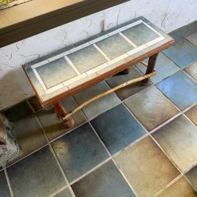 Sale Photo Thumbnail #83: Rustic low bench featuring a green and white ceramic tiled top set in a wooden frame with natural branch-style legs.