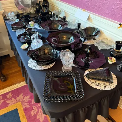 Sale Photo Thumbnail #101: Tabletop display featuring vintage black amethyst glassware, depression glass, cut crystal, and a silver-tone tray.