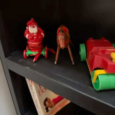 Sale Photo Thumbnail #146: Collection of vintage plastic and celluloid toys displayed on a shelf, including a wind-up Santa, a brown horse, and a toy tractor.