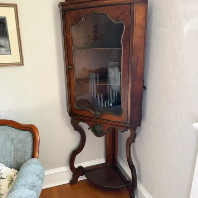 Sale Photo Thumbnail #134: Vintage wood corner hutch with a glass-front display cabinet, hand-painted floral pediment, and cabriole-style legs.