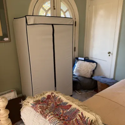 Sale Photo Thumbnail #171: Portable fabric garment wardrobe closet alongside various folded linens, blankets, and a fringed embroidered textile.