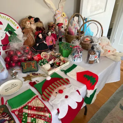 Sale Photo Thumbnail #181: Table displaying an assortment of Christmas and Easter decor, including felt stockings, red bauble ornaments, vintage dolls, woven baskets, and plush bunnies.