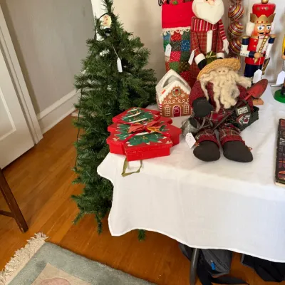 Sale Photo Thumbnail #178: Assorted Christmas decor display featuring a small artificial tree, Santa figurines, a nutcracker, gingerbread house decor, and festive gift boxes.