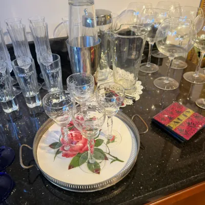 Sale Photo Thumbnail #158: Collection of assorted barware, including etched cocktail glasses on a floral serving tray, a metal cocktail shaker, and various wine glasses.